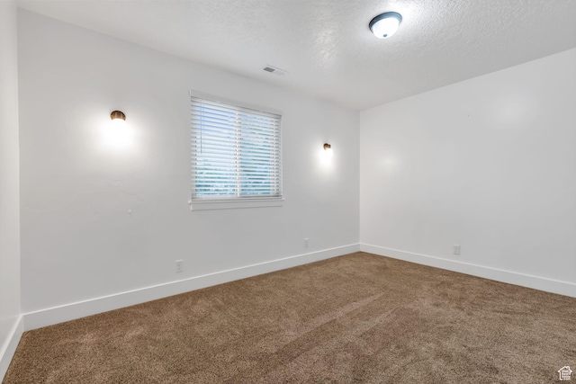 unfurnished room featuring baseboards, visible vents, a textured ceiling, and carpet