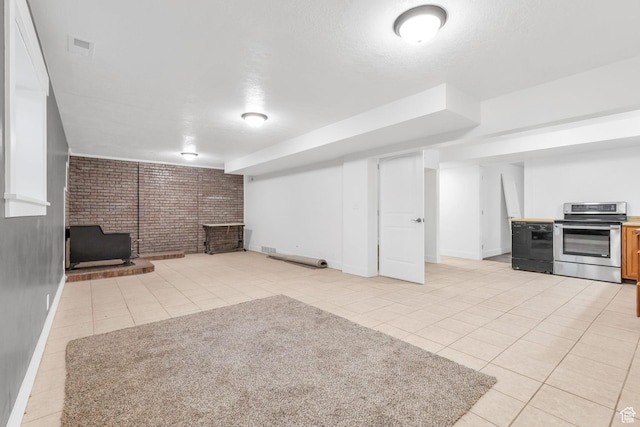 finished below grade area with light tile patterned floors, visible vents, baseboards, and brick wall