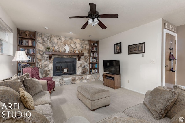 living room with built in shelves, ceiling fan, baseboards, carpet flooring, and a fireplace