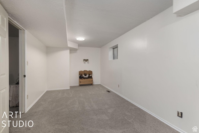 finished basement featuring carpet flooring, baseboards, and a textured ceiling