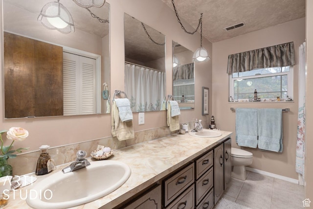 bathroom with double vanity, visible vents, toilet, and a sink