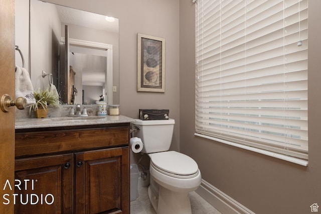 bathroom with vanity, toilet, and baseboards
