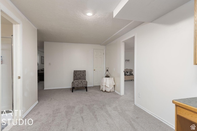 living area featuring baseboards, light colored carpet, and a textured ceiling