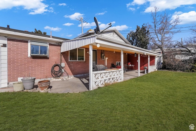 rear view of house with a yard, brick siding, and a patio area