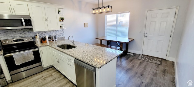 kitchen with a sink, open shelves, white cabinetry, appliances with stainless steel finishes, and a peninsula