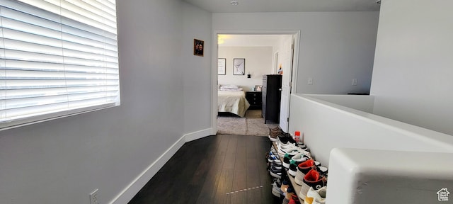 corridor featuring dark wood-type flooring and baseboards