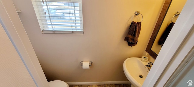 bathroom featuring toilet, baseboards, and a sink