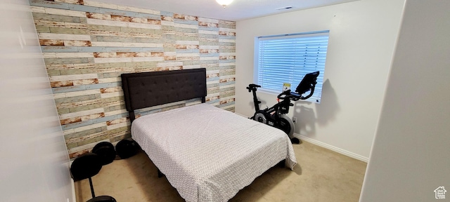 carpeted bedroom with an accent wall, baseboards, visible vents, and wood walls