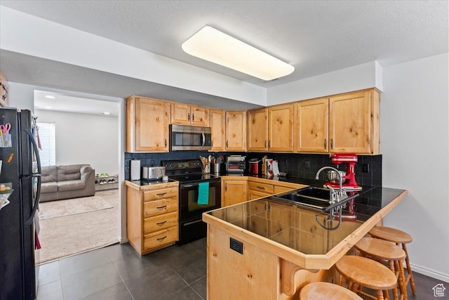1322 E 6175 S, South Ogden, UT 84405 - kitchen featuring black appliances, a kitchen bar, a peninsula, tasteful backsplash, and dark tile patterned flooring