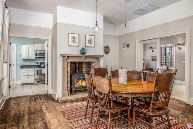 197 N 200 W, Kanab, UT 84741 - dining room with visible vents, baseboards, light wood-style floors, and a wood stove