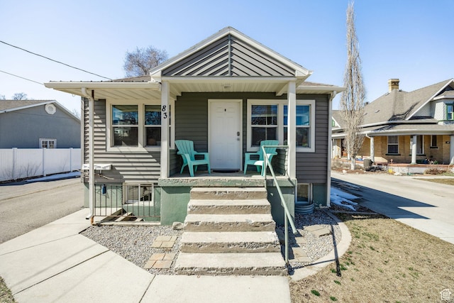 bungalow-style house with metal roof, covered porch, driveway, and fence