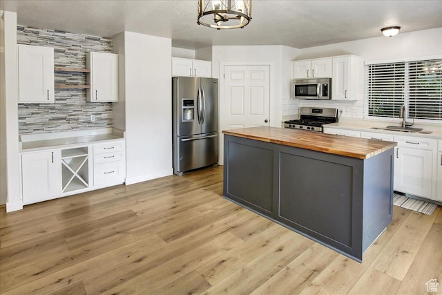 5772 Oakwood Dr, South Ogden, UT 84405 - kitchen with butcher block counters, appliances with stainless steel finishes, decorative backsplash, white cabinetry, and a center island