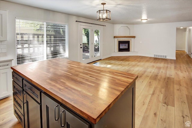 5772 Oakwood Dr, South Ogden, UT 84405 - unfurnished living room with light wood-style floors, a glass covered fireplace, a chandelier, and french doors