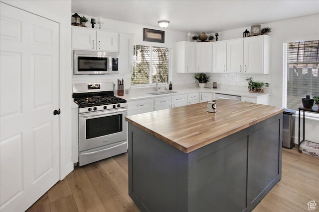 kitchen featuring light wood-type flooring, a sink, appliances with stainless steel finishes, tasteful backsplash, and butcher block counters