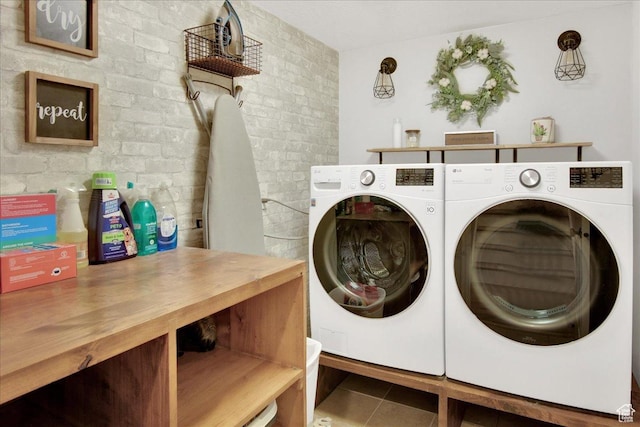 laundry area with tile patterned flooring, laundry area, independent washer and dryer, and brick wall