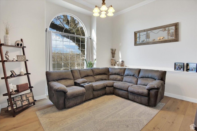 living room with crown molding, wood finished floors, baseboards, and a chandelier