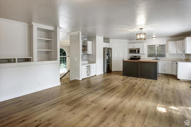 5772 Oakwood Dr, South Ogden, UT 84405 - kitchen with appliances with stainless steel finishes, butcher block counters, a center island, white cabinetry, and light wood-style floors