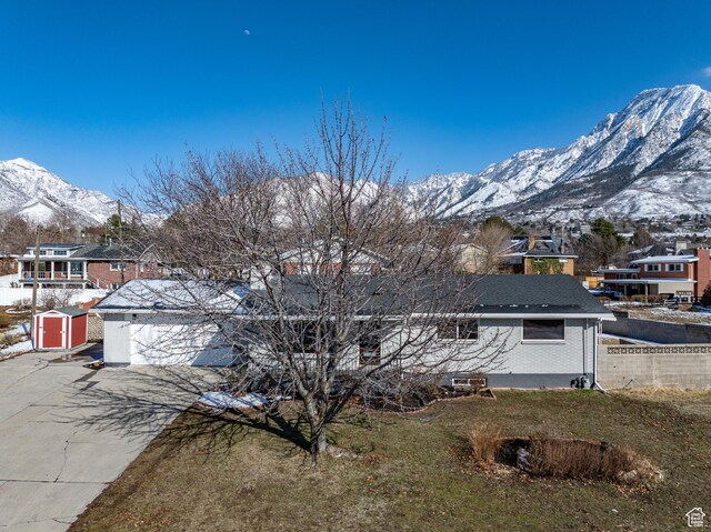 view of front of home featuring driveway, a shed, fence, a mountain view, and a garage