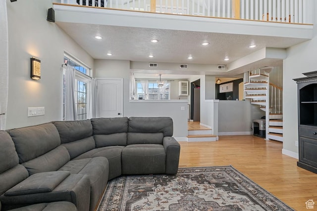 5964 W Jackling Way, West Jordan, UT 84081 - living area with baseboards, visible vents, stairs, light wood-style floors, and a textured ceiling