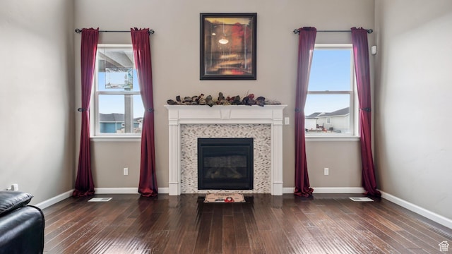 unfurnished living room with wood finished floors, baseboards, a glass covered fireplace, and visible vents