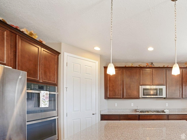 kitchen with recessed lighting, a textured ceiling, light stone countertops, stainless steel appliances, and pendant lighting