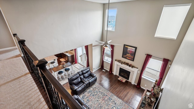 living room featuring baseboards, a high ceiling, ceiling fan, a fireplace, and hardwood / wood-style floors