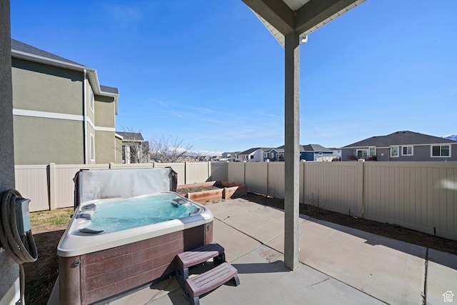 view of patio with a fenced backyard, a residential view, and a hot tub