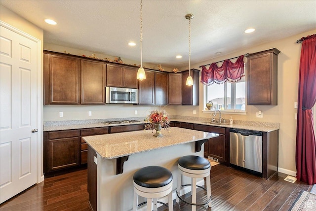 5663 W Yukon Park Ln S, Herriman, UT 84096 - kitchen featuring appliances with stainless steel finishes, dark wood-type flooring, a breakfast bar area, light stone countertops, and recessed lighting