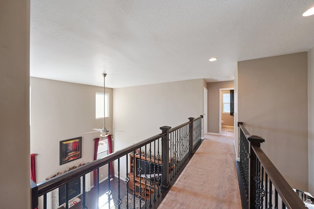 corridor with baseboards, an upstairs landing, a textured ceiling, recessed lighting, and carpet flooring