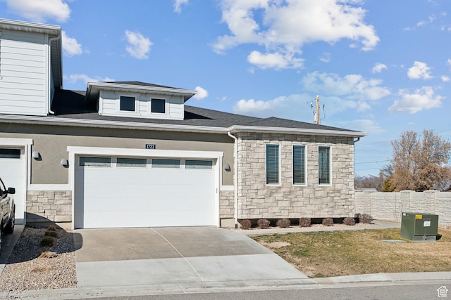 view of front of property with stucco siding, stone siding, fence, concrete driveway, and an attached garage