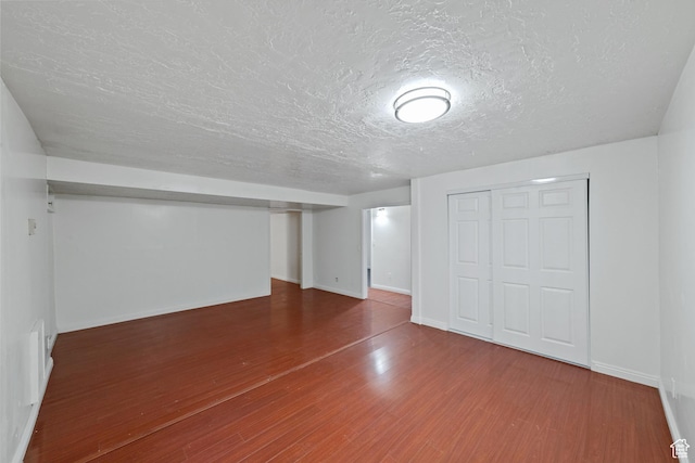 basement with baseboards, a textured ceiling, and wood finished floors