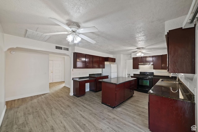 kitchen with visible vents, freestanding refrigerator, a sink, black range with electric cooktop, and dark countertops
