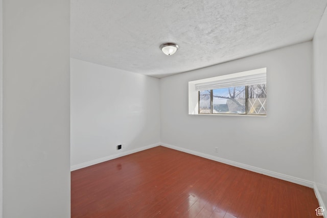 empty room featuring baseboards, a textured ceiling, and wood finished floors
