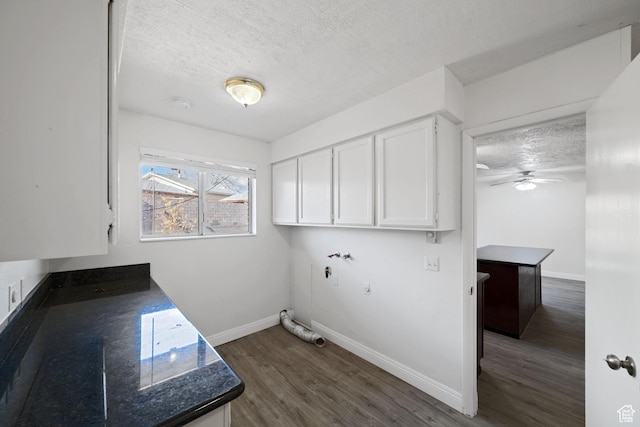 laundry area featuring baseboards, cabinet space, a textured ceiling, and dark wood-type flooring