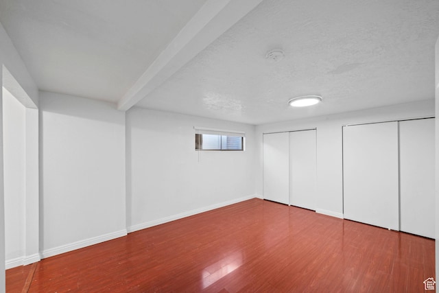 basement featuring wood finished floors, baseboards, and a textured ceiling