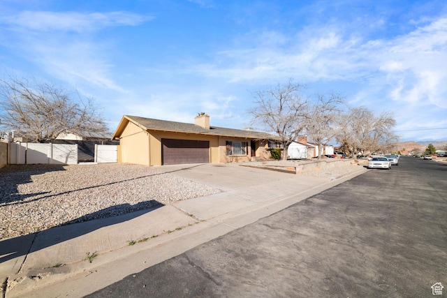 view of front facade featuring a gate, fence, stucco siding, concrete driveway, and a garage