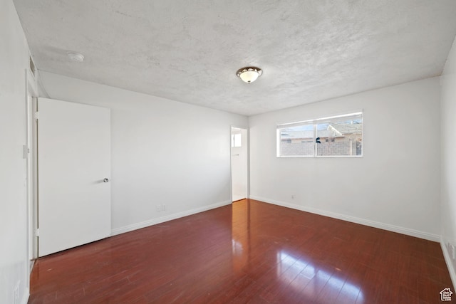 spare room featuring a textured ceiling, baseboards, and wood finished floors