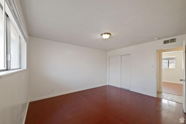 unfurnished room featuring wood finished floors, visible vents, and baseboards
