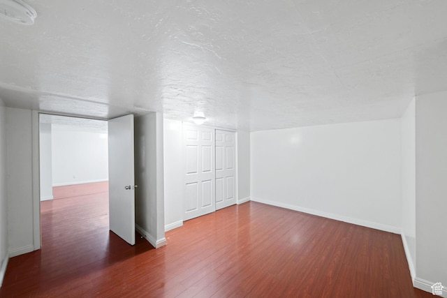 basement with wood finished floors, baseboards, and a textured ceiling