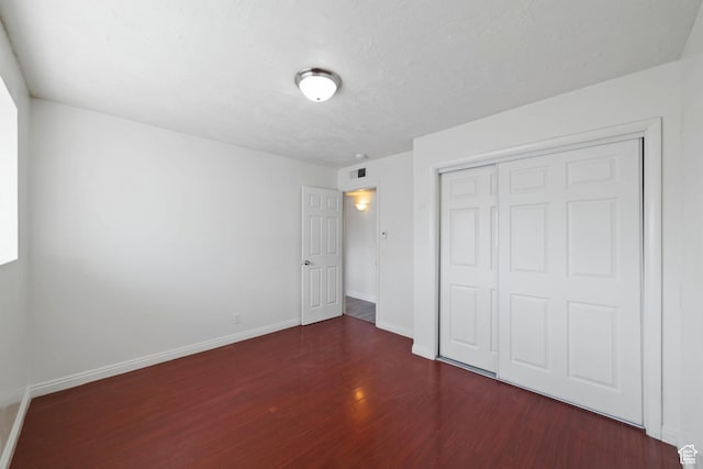 unfurnished bedroom with a closet, baseboards, and wood finished floors