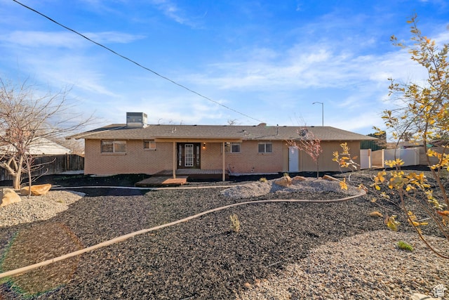 rear view of house featuring cooling unit, fence, and brick siding