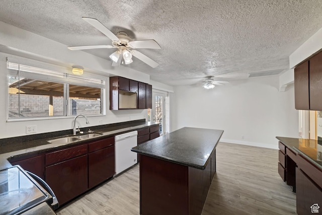 kitchen featuring dark countertops, dishwasher, light wood-style flooring, stove, and a sink