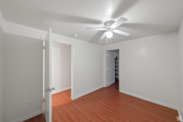empty room featuring a textured ceiling, a ceiling fan, baseboards, and wood finished floors