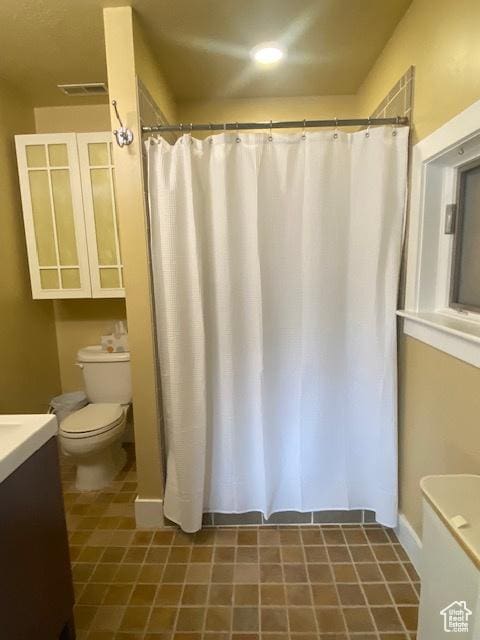 bathroom featuring curtained shower, visible vents, toilet, and vanity