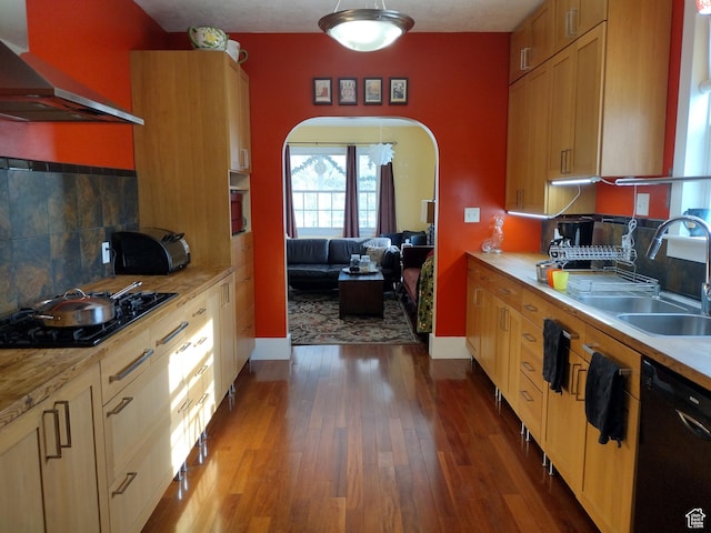 kitchen featuring light countertops, dark wood-style flooring, a sink, black appliances, and wall chimney exhaust hood