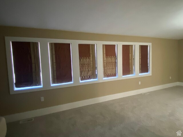 carpeted spare room featuring baseboards and visible vents
