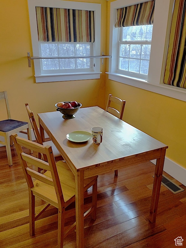 dining area with visible vents, baseboards, and wood finished floors