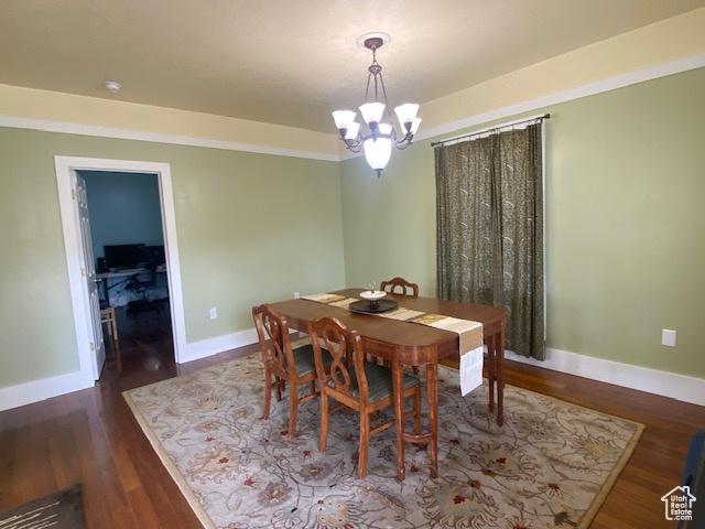 dining space with baseboards, wood finished floors, and a notable chandelier