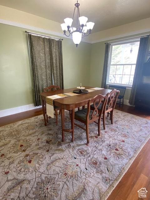 dining area featuring baseboards, wood finished floors, and an inviting chandelier