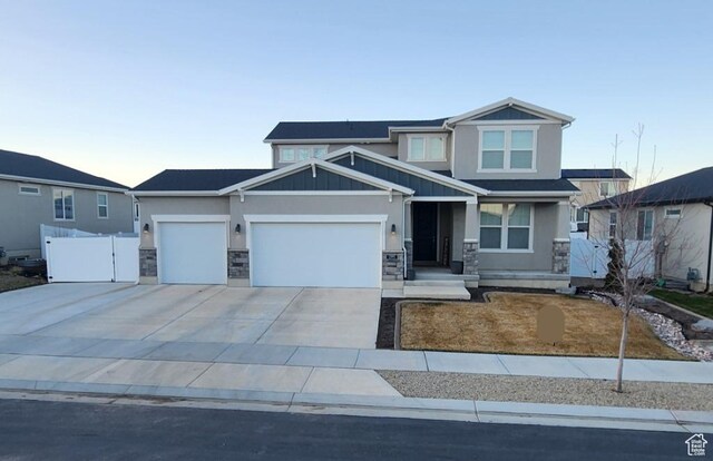 craftsman-style house with stone siding, fence, a garage, concrete driveway, and stucco siding